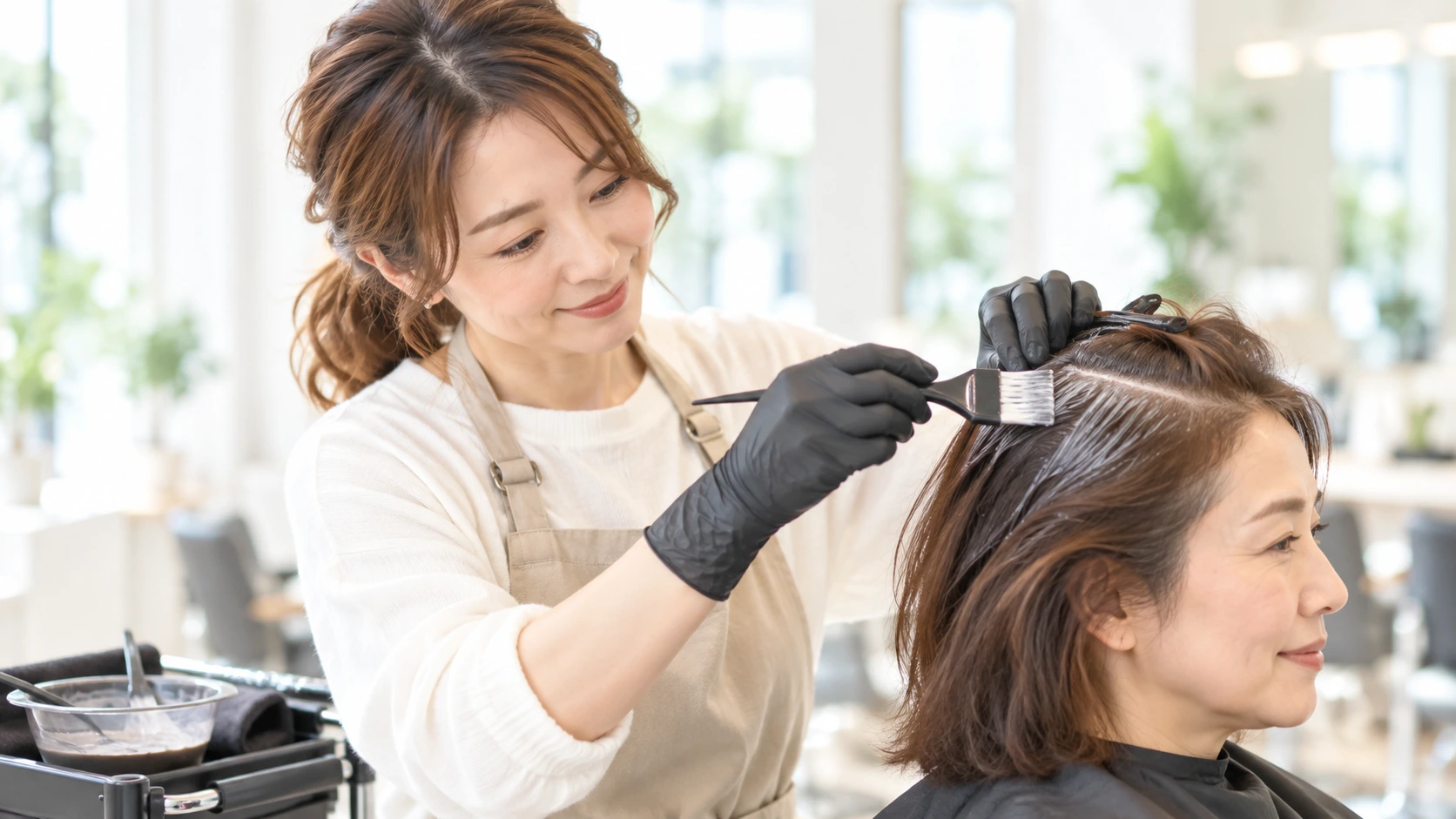 カラーを丁寧に塗布する美容師のイメージ
