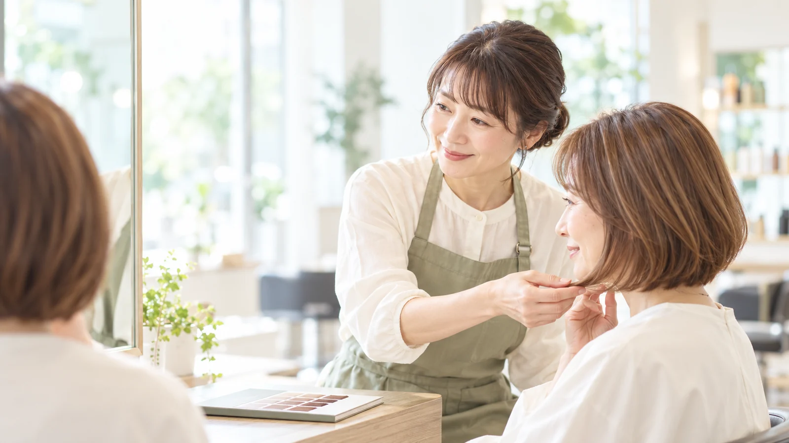 女性美容師がお客様の髪色と仕上がりを相談するイメージ